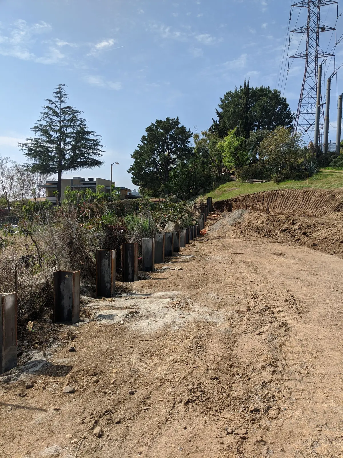 Row of vertical steel members beside a graded hillside path